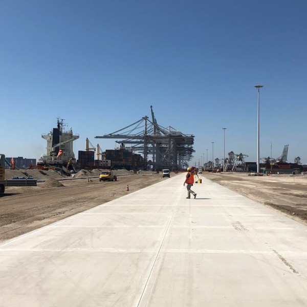 A construction worker walking on concrete on a job site