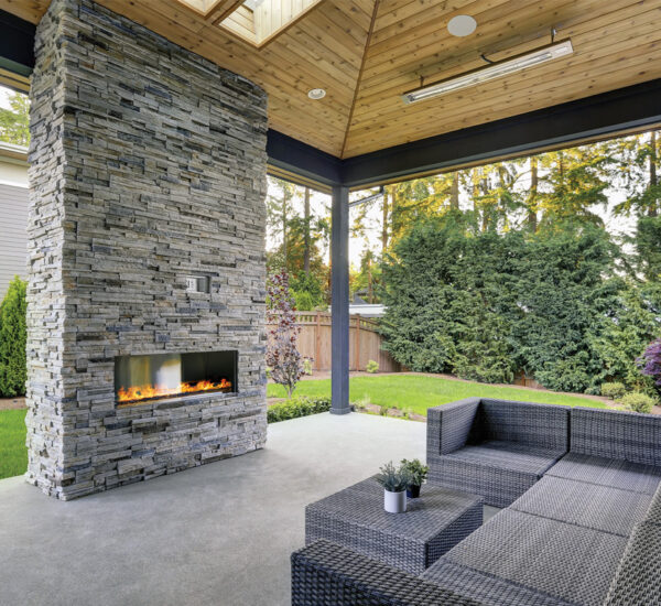 Artboard 2 A patio in a scenic backyard with a couch and fire pit.