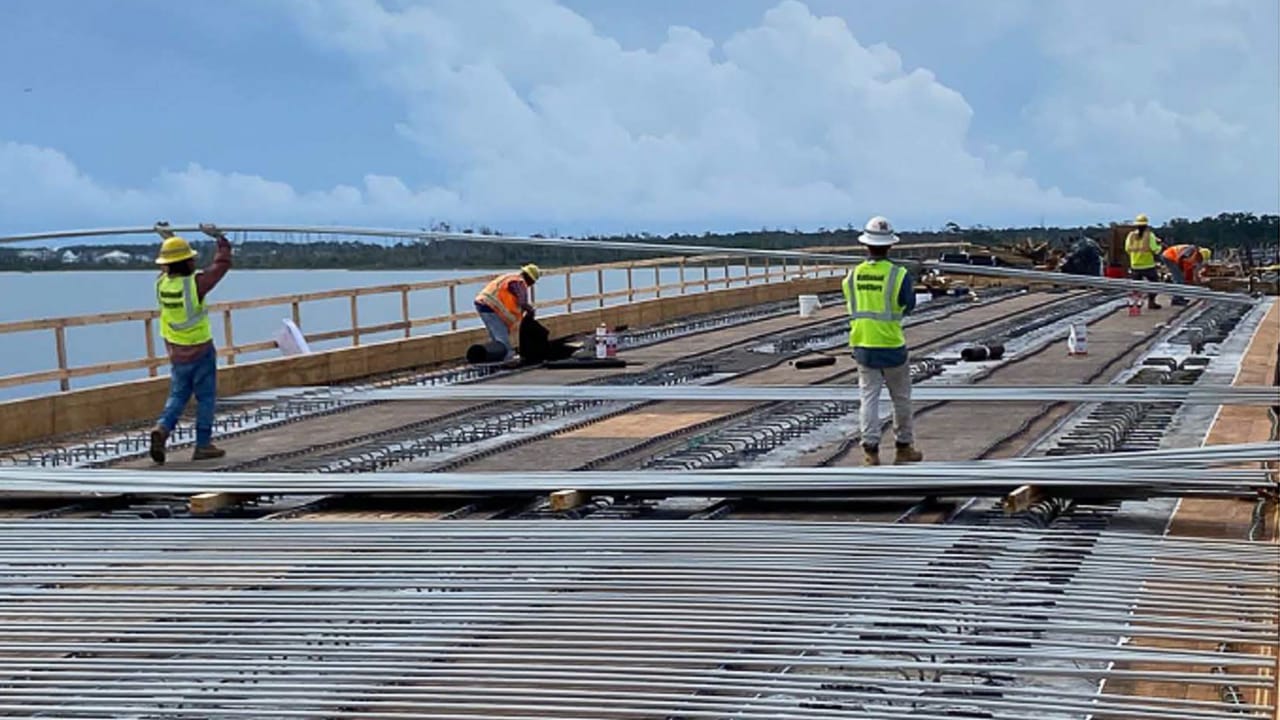 Construction workers carrying bars of fiberglass rebar on a bridge project.
