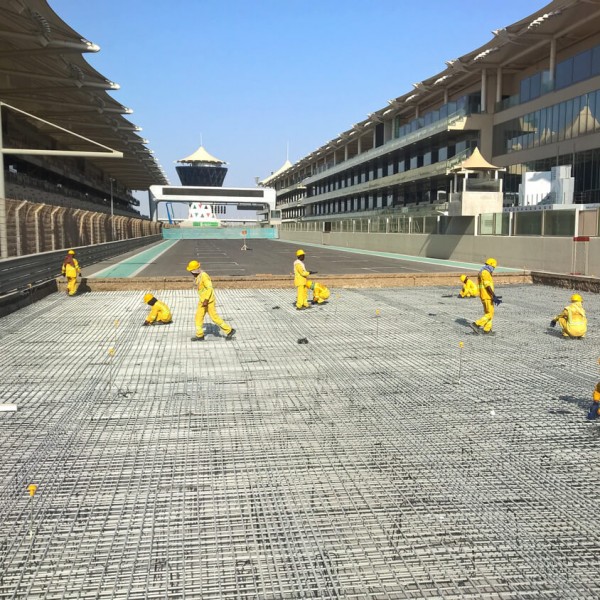 Multiple workers laying down fiberglass rebar at the Yas Island F1 Racetrack.