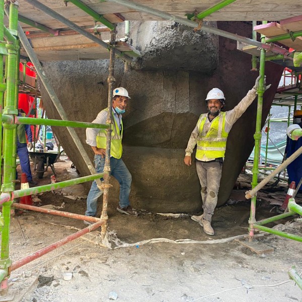 Two workers smiling while working on The Giant Sculpture.