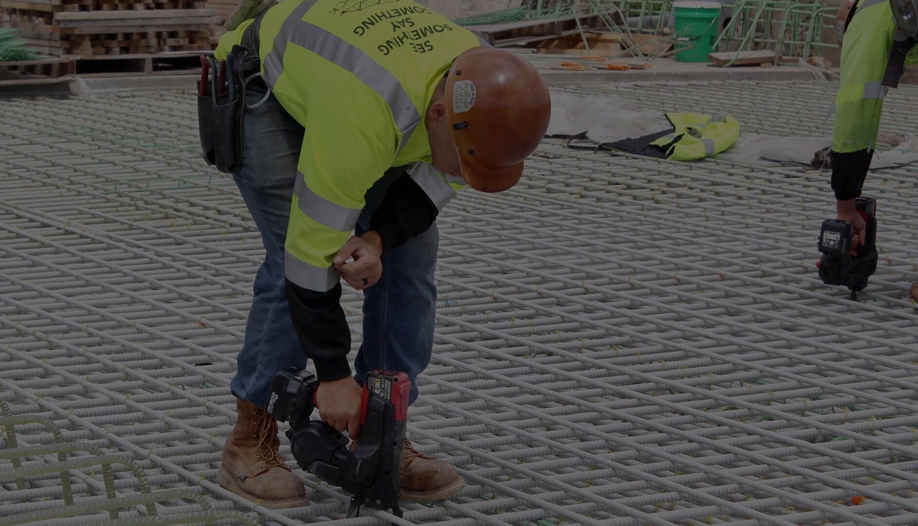 A construction worker using a tool to tie down fiberglass rebar on a job site