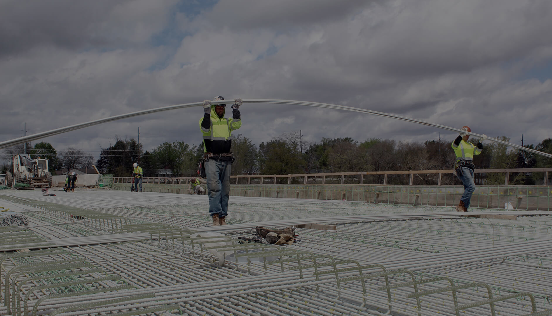 Two construction workers holding fiberglass rebar on a job site