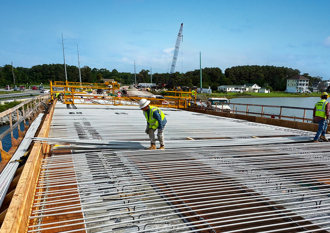 Workers on a job site using fiberglass rebar to reinforce a bridge project near the water