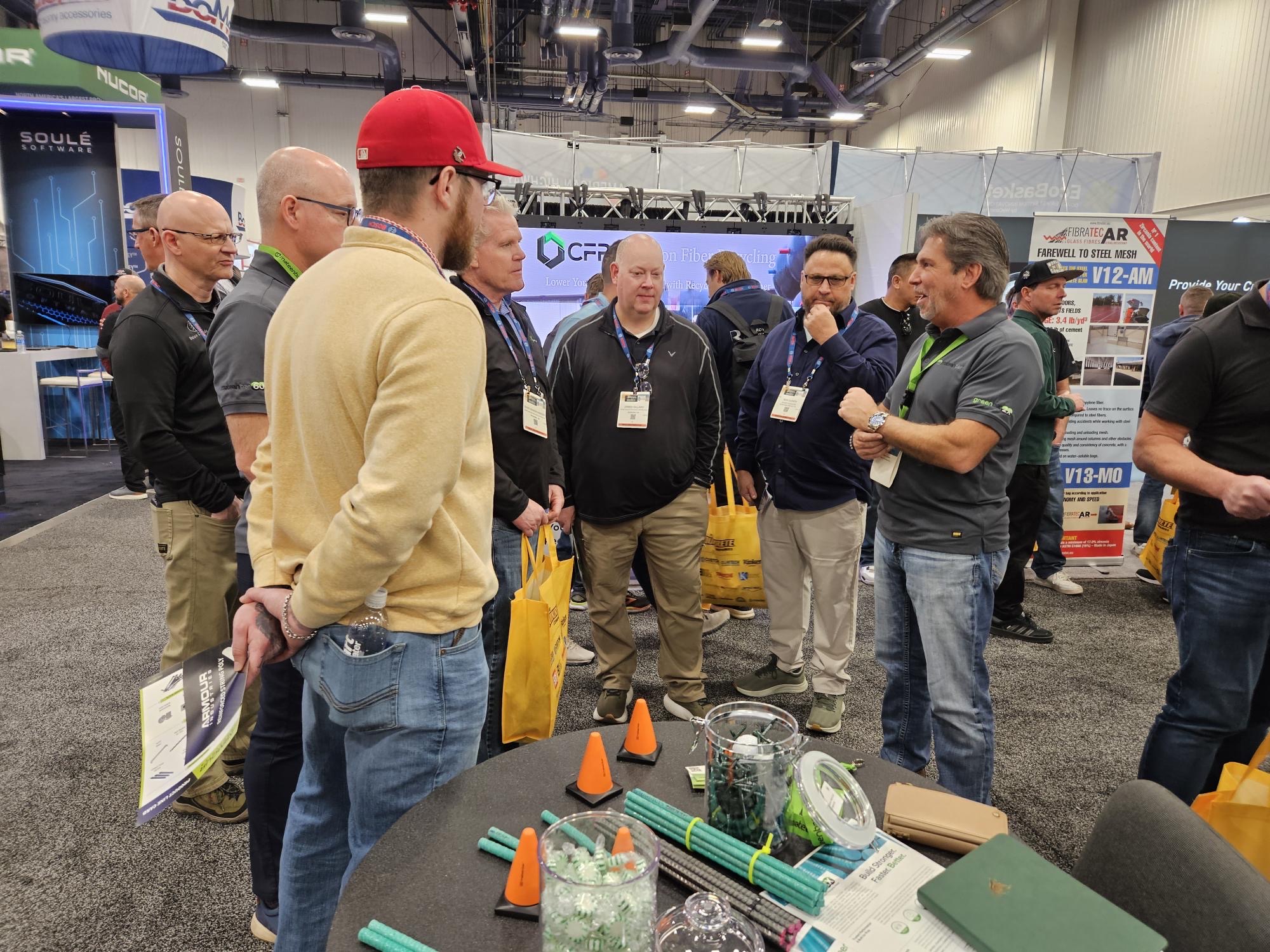 Seven people talking next to the Mateenbar booth at the World of Concrete 2025.