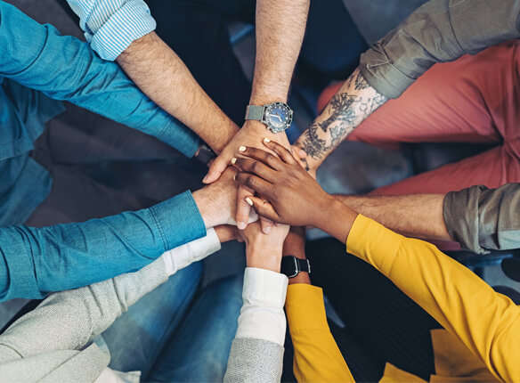 Five people putting their hands on top of each other