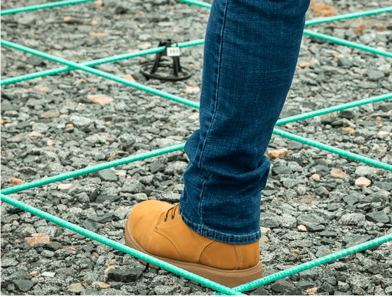 A boot stepping in between installed green fiberglass rebar